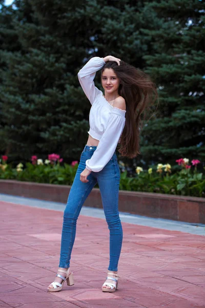 Jolie fille brune élégante en jean bleu et chemisier blanc — Photo