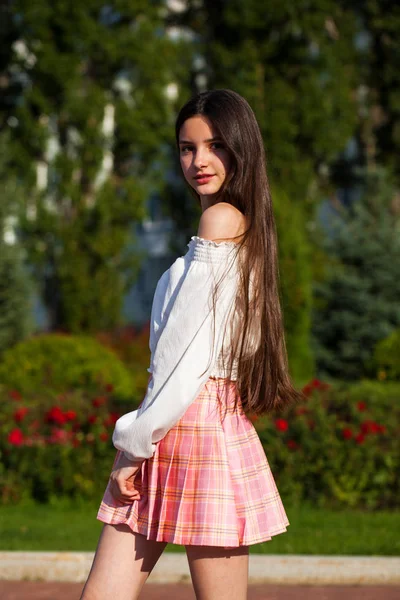 Chica morena bastante elegante en falda a cuadros y blusa blanca — Foto de Stock