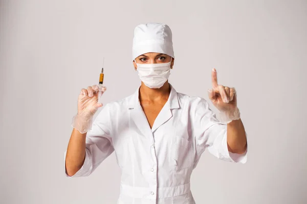 Enfermera joven con un abrigo blanco sostiene una jeringa en sus manos — Foto de Stock