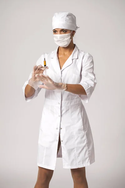 Enfermera joven con un abrigo blanco sostiene una jeringa en sus manos — Foto de Stock