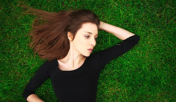 Retrato de vista superior de una joven hermosa mujer en vestido negro se encuentra — Foto de Stock