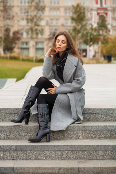 Портрет молодой красивой женщины в черном платье, сидящей на
 