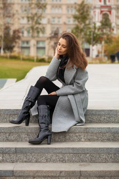 Porträt einer jungen schönen Frau in einem schwarzen Kleid, die auf — Stockfoto