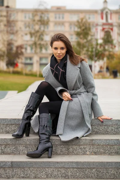 Portrait of a young beautiful woman in a black dress sitting on — Stock Photo, Image