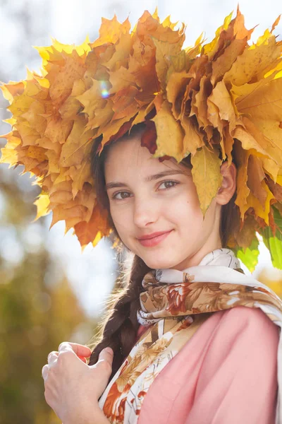 Jovem menina bonita feliz com uma grinalda de folhas de bordo em autu — Fotografia de Stock