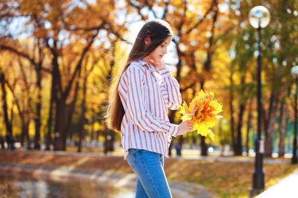 Όμορφη μελαχρινή μικρό κορίτσι που ποζάρει στο φθινόπωρο πάρκο στο παρασκήνιο — Φωτογραφία Αρχείου