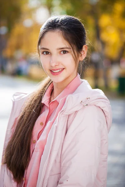 Linda niña morena posando en el fondo del parque de otoño —  Fotos de Stock