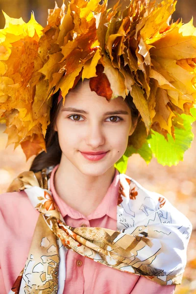 Lycklig ung vacker flicka med en krans av lönnlöv i autu — Stockfoto