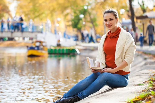 Junge schöne Frau liest im Herbstpark ein Buch — Stockfoto