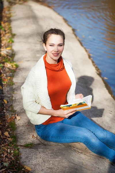 Jovem bela mulher lendo um livro no parque de outono — Fotografia de Stock