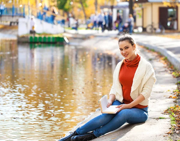 Jovem bela mulher lendo um livro no parque de outono — Fotografia de Stock