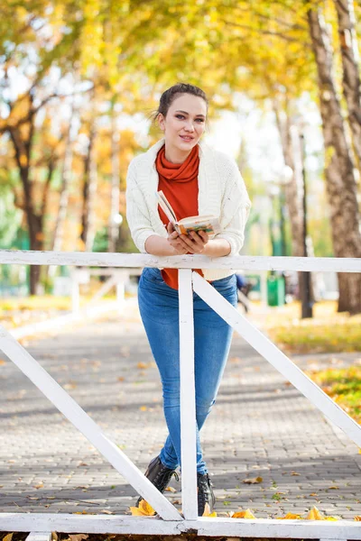 Genç güzel kadın sonbahar Park bir kitap okuma — Stok fotoğraf