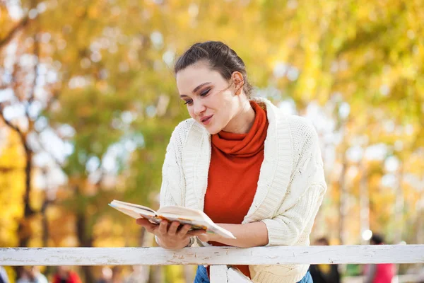 Junge schöne Frau liest im Herbstpark ein Buch — Stockfoto