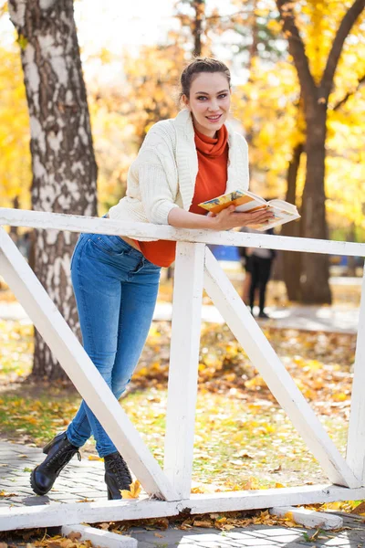 Jovem bela mulher lendo um livro no parque de outono — Fotografia de Stock