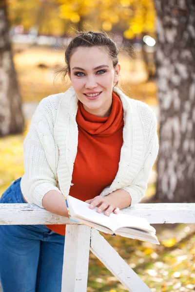 Jonge mooie vrouw lezen van een boek in de herfst park — Stockfoto