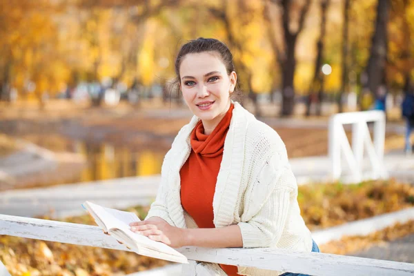 年轻漂亮的女人在秋天公园看书 — 图库照片
