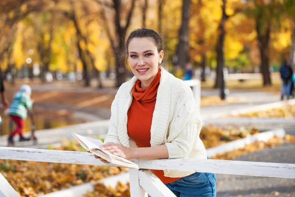 Молода красива жінка читає книгу в осінньому парку — стокове фото