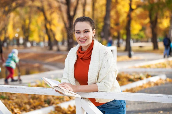 Молодая красивая женщина читает книгу в осеннем парке — стоковое фото