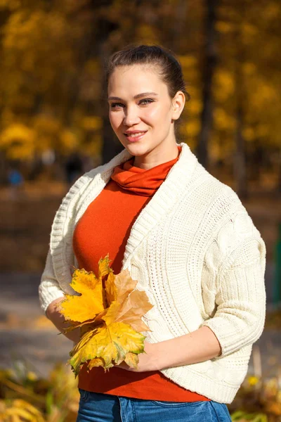 Sonbahar parkında poz veren kot pantolonlu güzel bir kadın. — Stok fotoğraf