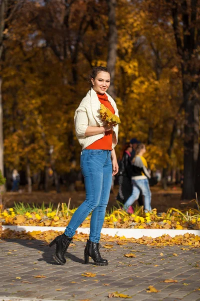 Jonge mooie vrouw in blauwe jeans poseren in de herfst park — Stockfoto