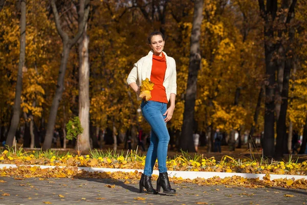 Giovane bella donna in jeans blu in posa nel parco autunnale — Foto Stock