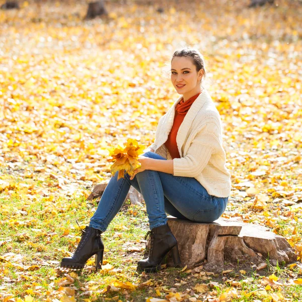 Young beautiful woman in blue jeans posing in autumn park — Stock Photo, Image