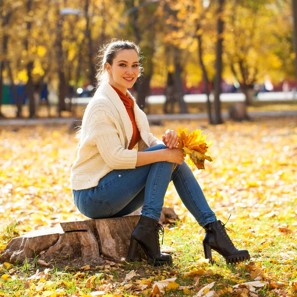 Молодая красивая женщина в синих джинсах позирует в осеннем парке — стоковое фото