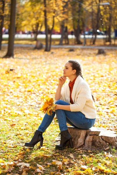 Молодая красивая женщина в синих джинсах позирует в осеннем парке — стоковое фото