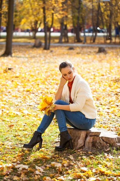 Jonge mooie vrouw in blauwe jeans poseren in de herfst park — Stockfoto