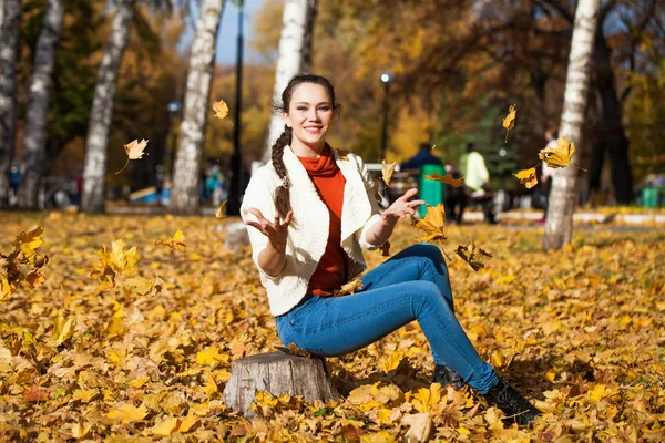 Young beautiful woman in blue jeans posing in autumn park — Stock Photo, Image