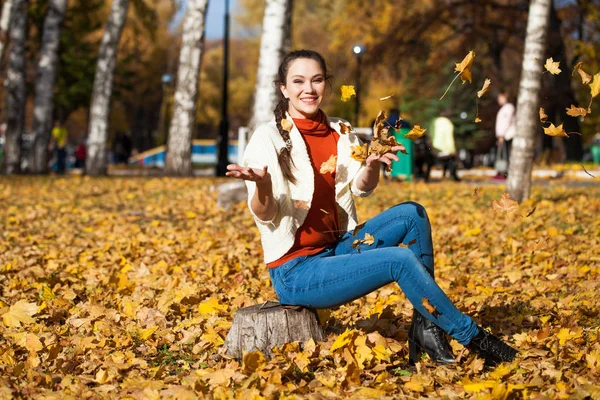 가을 공원에서 포즈를 취하고 있는 청바지를 입은 아름다운 아가씨 — 스톡 사진