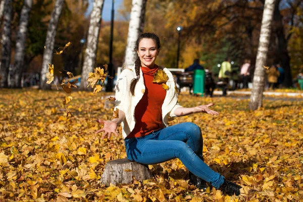 Young beautiful woman in blue jeans posing in autumn park — Stock Photo, Image