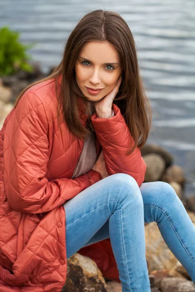 Joven mujer con estilo en una chaqueta de plumón de salmón posando en un backgrou —  Fotos de Stock