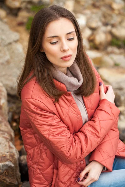 Joven mujer con estilo en una chaqueta de plumón de salmón posando en un backgrou —  Fotos de Stock