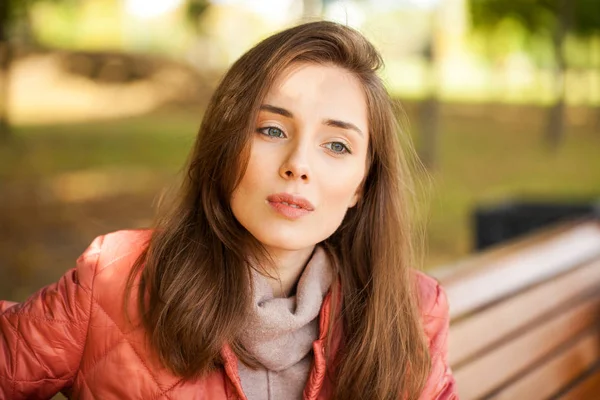 Joven mujer con estilo en una chaqueta de plumón de salmón posando en un backgrou — Foto de Stock