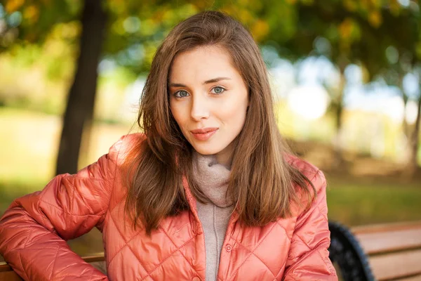 Joven mujer con estilo en una chaqueta de plumón de salmón posando en un backgrou — Foto de Stock