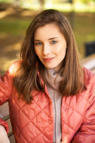 Junge stylische Frau in lachsfarbener Daunenjacke posiert auf einem Hinterteil — Stockfoto