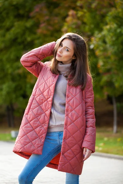 Joven mujer con estilo en una chaqueta de plumón de salmón posando en un backgrou —  Fotos de Stock