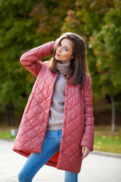 Junge stylische Frau in lachsfarbener Daunenjacke posiert auf einem Hinterteil — Stockfoto