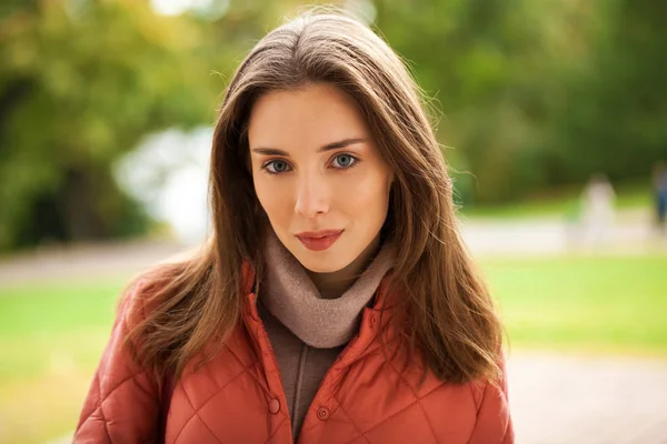 Junge stylische Frau in lachsfarbener Daunenjacke posiert auf einem Hinterteil — Stockfoto