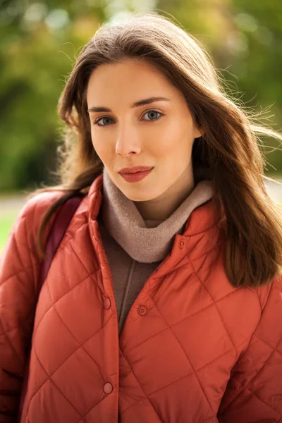 Joven mujer con estilo en una chaqueta de plumón de salmón posando en un backgrou —  Fotos de Stock