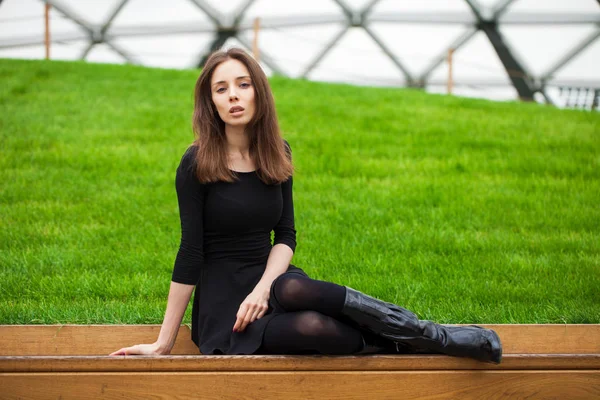 Jovem bela mulher sentada em um banco no parque de outono — Fotografia de Stock