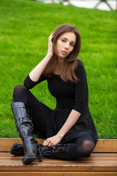 Young beautiful woman sitting on a bench in the autumn park — Stock Photo, Image