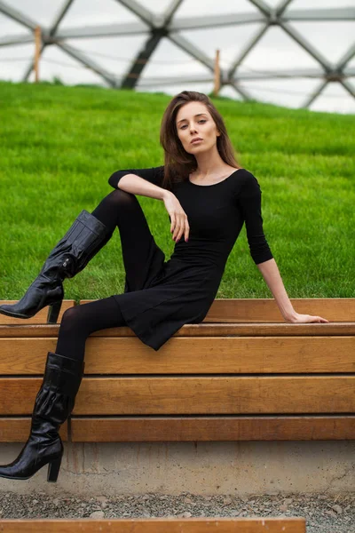Jeune belle femme assise sur un banc dans le parc d'automne — Photo