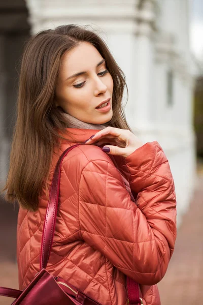 Young stylish woman in a salmon down jacket posing on a backgrou — Stock Photo, Image