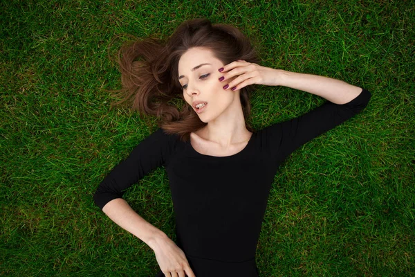 Retrato de vista superior de una joven hermosa mujer en vestido negro se encuentra —  Fotos de Stock