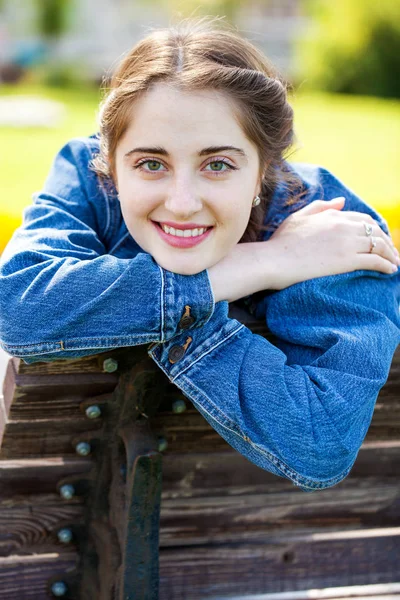 Belle fille dans une veste en denim assis sur un banc en été par — Photo