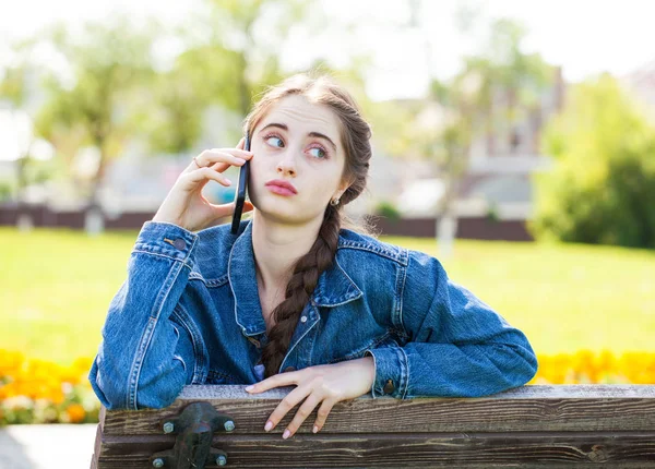 Menina em jeans jaqueta chamando por telefone — Fotografia de Stock