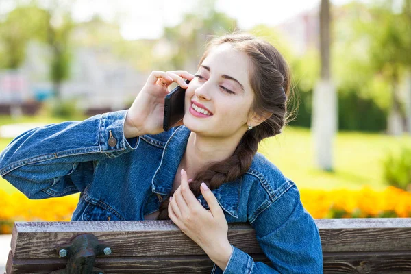 Ung flicka i jeans jacka ringer per telefon — Stockfoto
