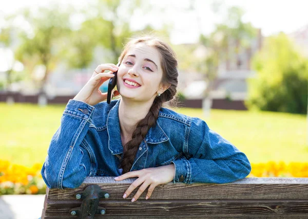 Menina em jeans jaqueta chamando por telefone — Fotografia de Stock